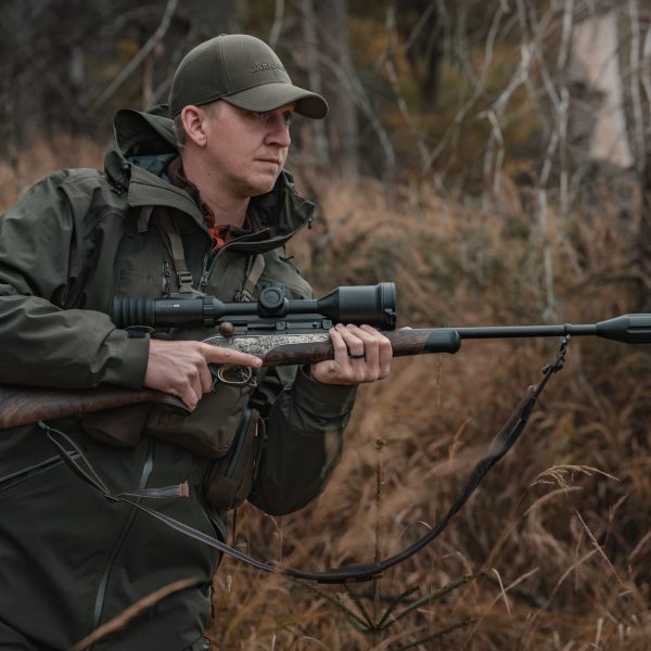 Hunter holding a scoped rifle in scrub